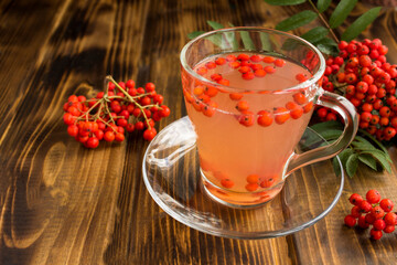 Autumn drink with red rowan on wooden surface. Closeup.
