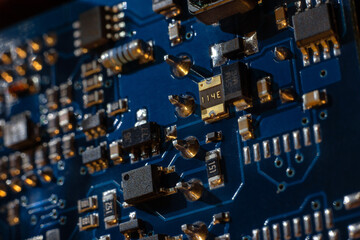 Close-up of a blue printed circuit board (PCB) with stripes of conductors between a transistor and...