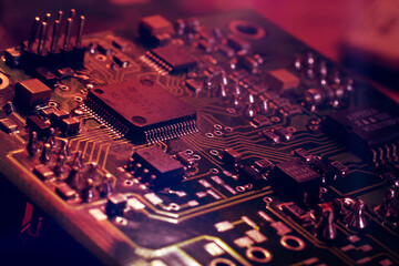 Close-up. Red neon abstract tech computer background. Printed circuit board (PCB) and electronic components of the chip. Artificial intelligence and technology - obrazy, fototapety, plakaty