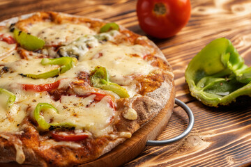 Vegetarian pizza with paprika on a wholemeal dough on a wooden Board near the ingredients, close-up