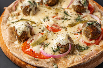 Vegetarian pizza with falafel and wholemeal dough on a black table close-up