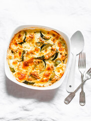 Zucchini, chicken breast, mozzarella cheese casserole on a light background, top view