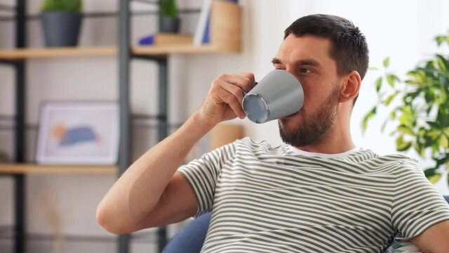 people and leisure concept - portrait of happy smiling young man drinking coffee at home
