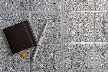 Flat lay fountain pen and notebook on decorative tin background