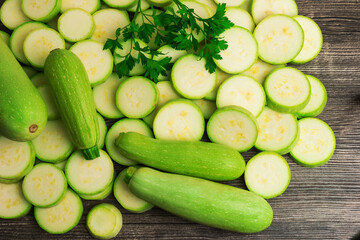Fresh green squash, zucchini, courgette, slices and parsley  on wooden background
