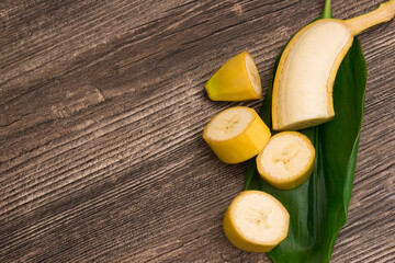 Raw organic yellow bananas with green leaf on wooden background - 369313830