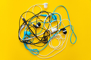 Bunch of different earphones isolated on yellow background. Color conceptual. Conceptual...