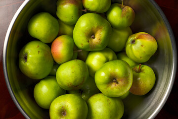 Recipiente con pequeñas manzanas verdes de una huerta