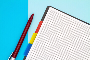 Top view of open blank notebook and pen on a colored background