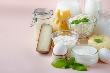 Fresh dairy products, milk, cottage cheese, eggs, yogurt, sour cream and butter on pink background