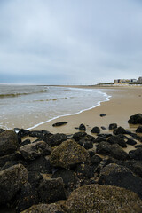 Fototapeta na wymiar Black stones on the North Sea beach. Landscape photo with the North Sea and a beach on an East Frisian island. Clouds over the North Sea