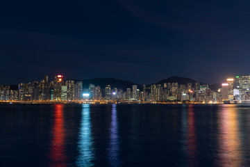 Fototapeta na wymiar Hong Kong cityscape at night over Victoria Harbor with clear sky and urban skyscrapers.