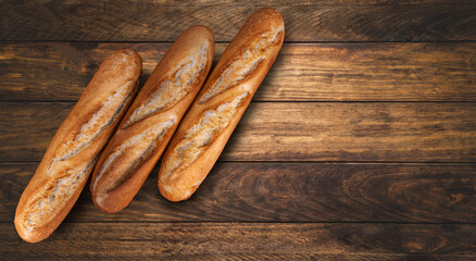 three French buggets lie on a wooden table. Place for text