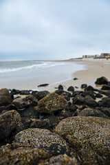 Fototapeta na wymiar Black stones on the North Sea beach. Landscape photo with the North Sea and a beach on an East Frisian island. Clouds over the North Sea