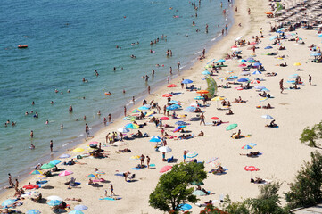 sea beach with tourists on sunny day, aerial photo