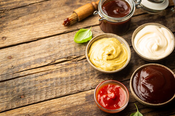 Classic set of sauces, American yellow mustard, ketchup, barbecue sauce, mayonnaise on wooden...