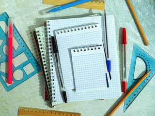 Notebooks, notepads, pens, rulers and other items on a green background. Empty space for text. Background with stationery for business, industry, education.