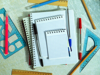 Notebooks, notepads, pens, rulers and other items on a green background. Empty space for text....