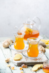 Ginger tea in a glass cup with lemon and mint on light background