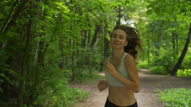 Young sporty woman jogging through the forest