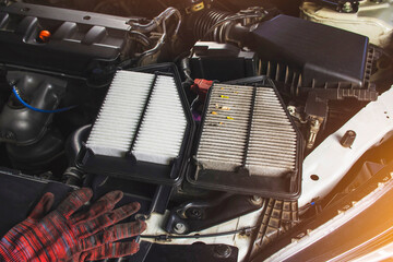 Car air filter with new and old placed on car chassis in engine room of a car