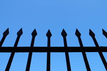 fragment of a forged fence against the background of the clear sky