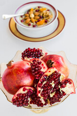 Fresh pomegranate fruits on white surface with ashure bowl.Selective focus of vertical image