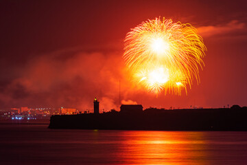 Festive salute over the city of Sevastopol on the day of the Navy. Bright multicolored flashes of fireworks. The concept of the celebration. Night shooting of the city. Silhouette of the lighthouse.