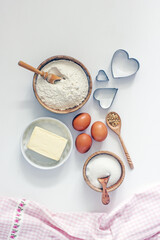 Ingredients for home baking cookies butter, sugar, eggs, flour, cookie cutters, rolling pin on a light background, top view. DIY homemade cookies background
