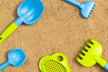 Fototapeta na wymiar Sandbox. Children's sand toys outdoors. Background with colored shovel, rake, sieve and bucket. Summer concept.