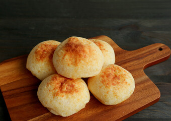Fresh baked homemade Brazilian cheese breads or Pao de Queijo on a wooden breadboard