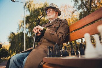 Profile side photo of old man lonely chess player sit bench walk stick have no contestant in autumn...