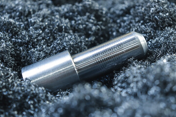 A product turned on a lathe close-up against a background of metal shavings. Metalworking at the...