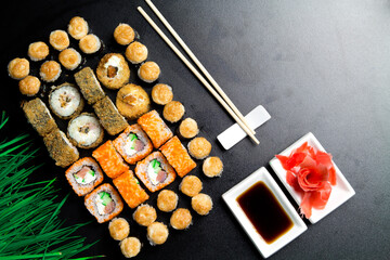 Sushi set served on a stone slate on a dark background. Sushi rolls with salmon, tuna, cucumber, baked, wasabi, soy sauce and ginger. Sushi rolls photo for menu and advertising