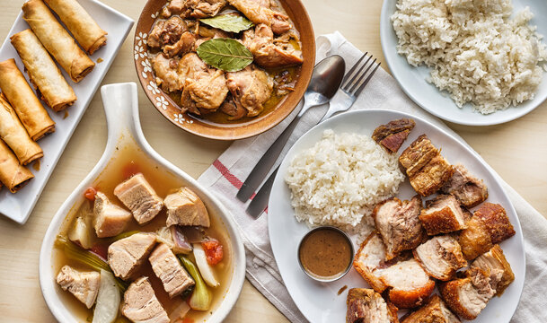filipino dinner with sinigang, lechon kawali, and chicken adobo top down composition