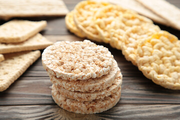 Various types of healthy whole grain crispbreads on brown wooden background.