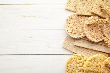 Various types of healthy whole grain crispbreads on white wooden background.