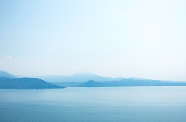 View of Lake Garda in the early morning or evening. The water is calm, the sky is partly cloudy. Small boats dance on the water. The mood is dreamy. morning Mood