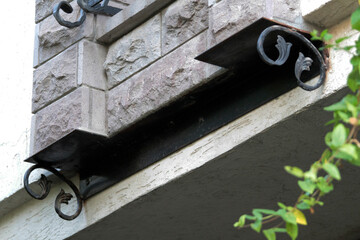 Decorative, weight-bearing accessory used on the exterior of buildings made of iron work. Decoration piece made of wrought iron. Exterior part made of iron.