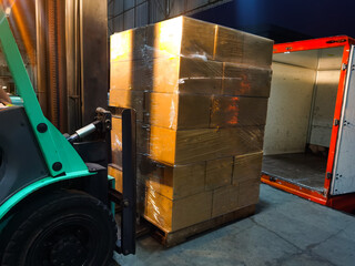 Worker driving forklift loading and unloading shipment carton boxes and goods on wooden pallet from container truck to warehouse cargo storage in logistics and transportation industrial 