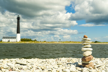 Stones balance, hierarchy stack over blue sea with lighthouse at background. Well-being, freedom...