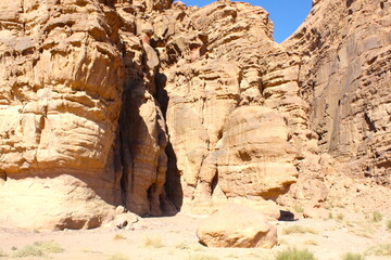 Deserted landscape view of the Wadi Rum desert, close-up of a rock cliff,  mountain and dunes, orange and red, Jordan.