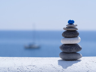 Fototapeta na wymiar Rock zen pyramid of colorful pebbles on the background of the sea and boat. Concept of Life balance, harmony and meditation