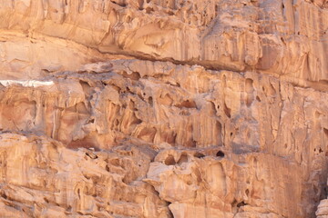 Deserted landscape view of the Wadi Rum desert, close-up of a rock cliff,  mountain and dunes, orange and red, Jordan.