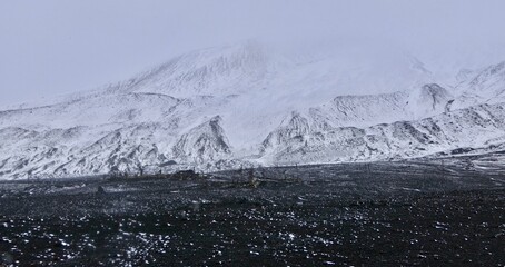 Antarctica, deception island, ruin in storm, snow on volcanic black stone