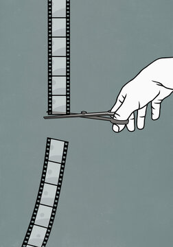 Hand with scissors cutting film negative