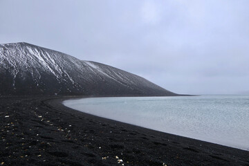 Antarctica, deception island, crate with volcanic black stone, white snow, water