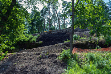 Security concept. Strengthening the mountain slope with construction equipment, artificial mesh,...