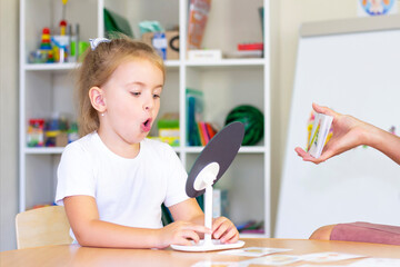 developmental and speech therapy classes with a child-girl. Speech therapy exercises and games with a mirror and cards