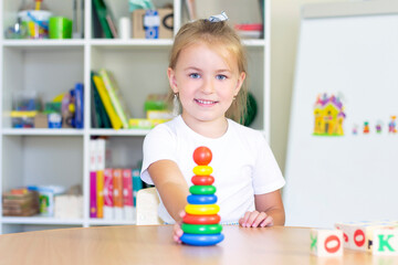 developmental and speech therapy classes with a child-girl. Speech therapy exercises and games with a colored pyramid